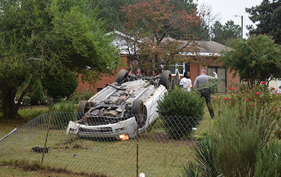 Two hurt when car flips into a yard